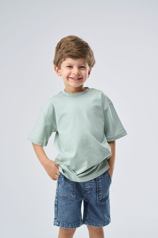 Young boy wearing a mint green oversized t-shirt