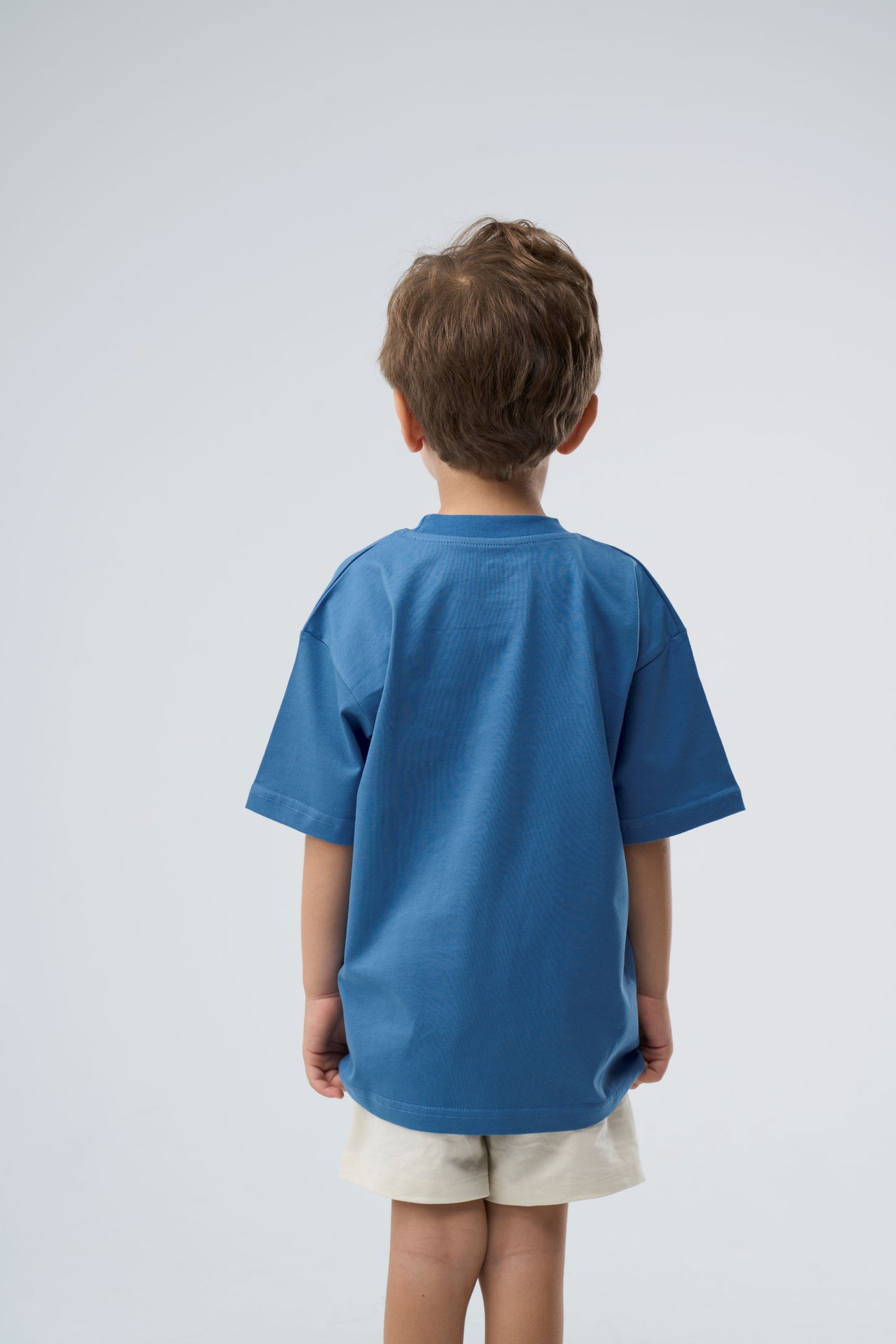 Young boy wearing a blue oversized t-shirt - back view